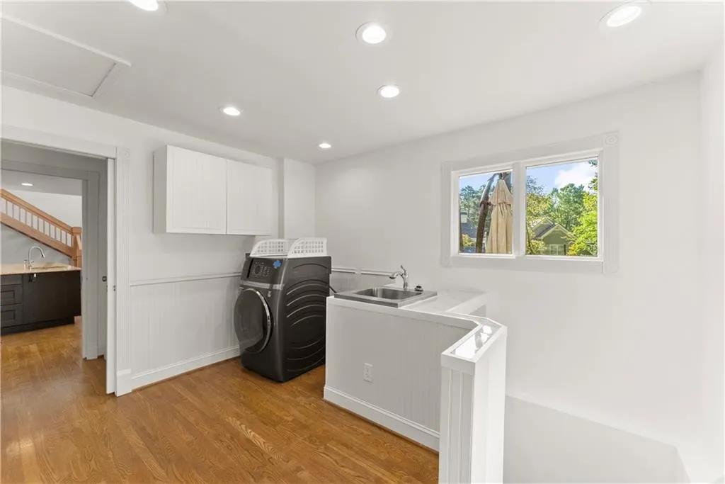 Laundry room featuring recessed lighting, cabinet space, light wood finished floors, a wainscoted wall, and washing machine and dryer