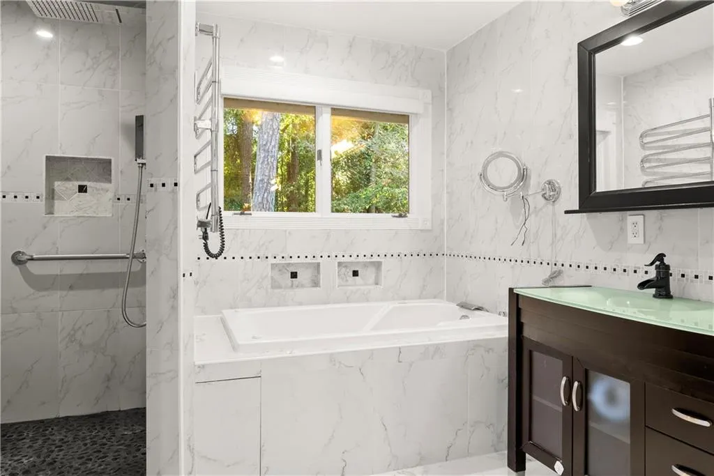 Master Bathroom with tile walls, a bath, vanity, and a marble finish shower