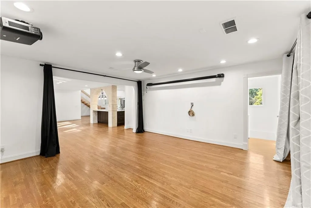 Cinema featuring light wood-type flooring, recessed lighting, ceiling fan, and a barn door