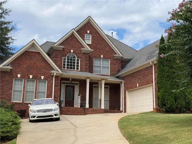 Traditional-style home with a porch, brick siding, and roof with shingles