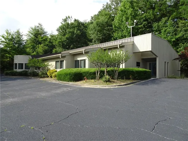 Single-story commercial building with light-colored siding and a dark roofline