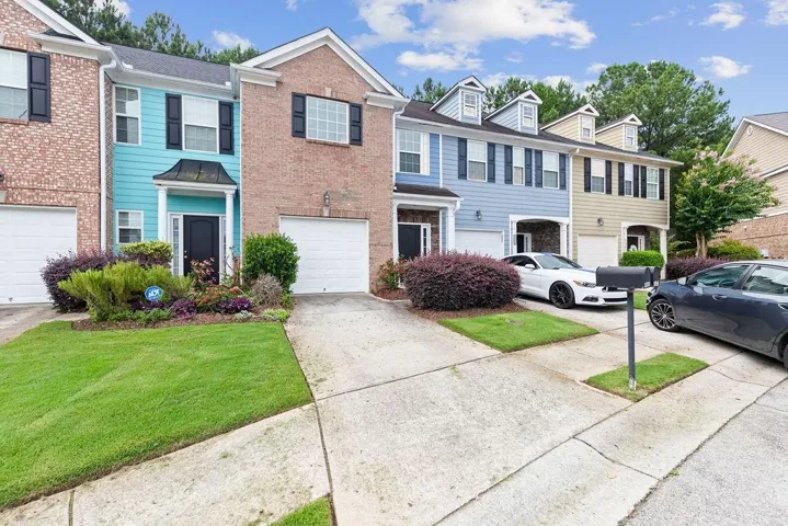 Colonial home featuring a garage, driveway, brick siding, and a front lawn