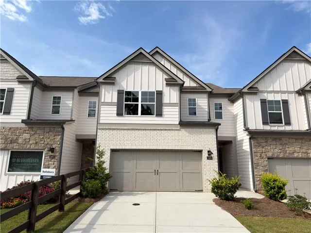 Contemporary exterior featuring white siding, brick accents, stone veneer, dark shutters, and a two-car garage