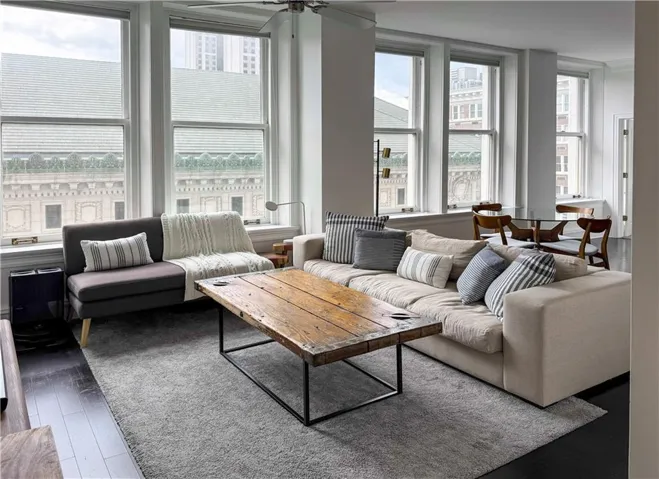Spacious living area featuring multiple large windows, dark wood-finish flooring, a light gray area rug, and high ceilings