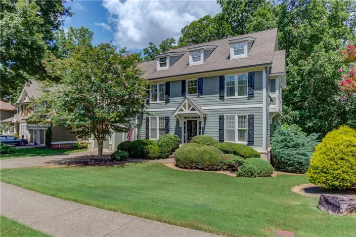 Classic architectural facade featuring dormer windows, a covered front entry, and horizontal siding