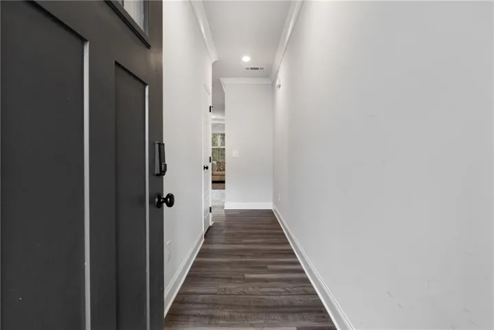 Corridor featuring ornamental molding and dark wood-type flooring
