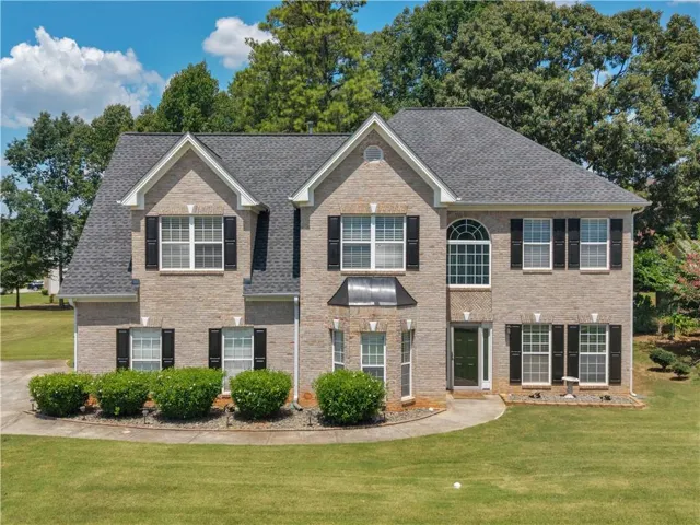 Brick facade with multiple gables, arched window, dark shutters, and a dark front door