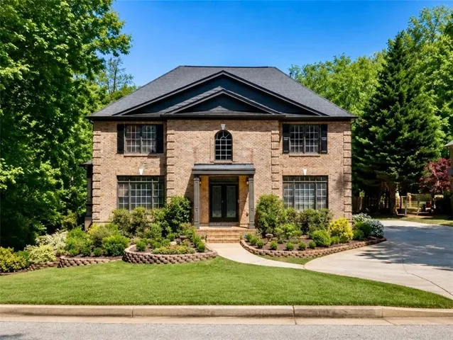 Traditional brick exterior with dark shingle roof and black shutters