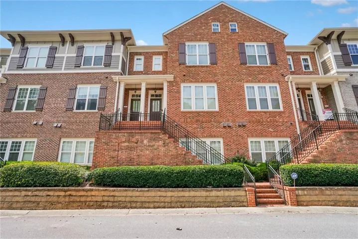 Traditional brick townhome facade featuring white-framed windows with dark shutters