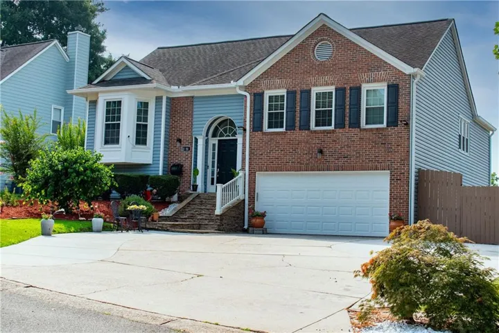 Traditional-style residence featuring a brick facade, light blue siding, and a two-car garage