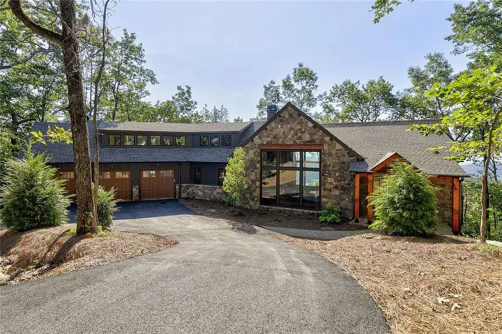 Stone and wood-sided exterior with a natural wood-finish garage door