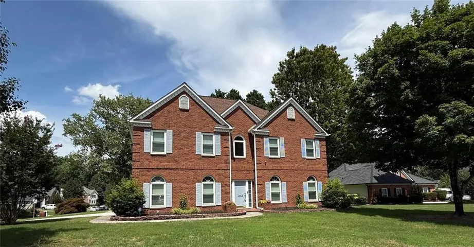 Two-story brick facade residence featuring a symmetrical design, light-colored shutters, arched first-story windows, and a prominent front gable