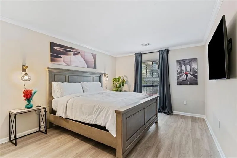 Bedroom featuring light wood-type flooring and ornamental molding Bedroom featuring light wood-type flooring and ornamental molding