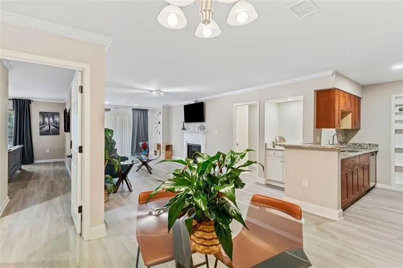 Dining room featuring light wood-type flooring, a fireplace, ornamental molding, and a chandelier Dining room featuring light wood-type flooring, a fireplace, ornamental molding, and a chandelier