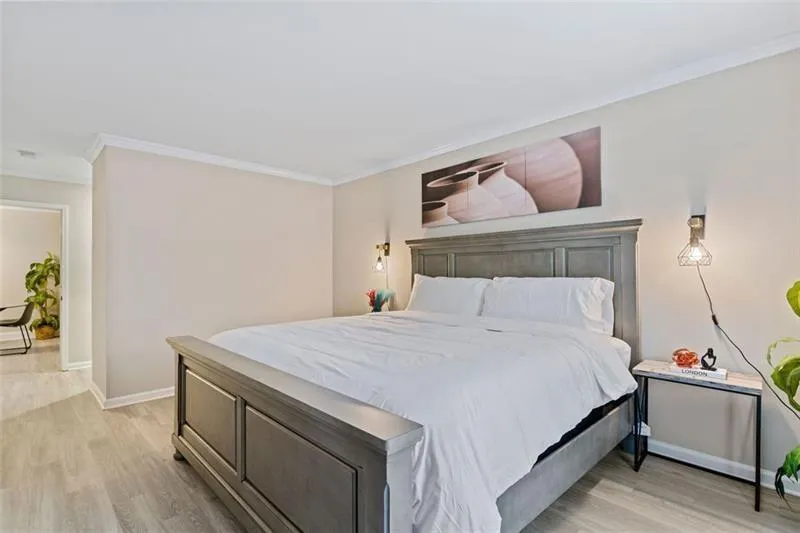 Bedroom featuring ornamental molding and light wood-type flooring Bedroom featuring ornamental molding and light wood-type flooring