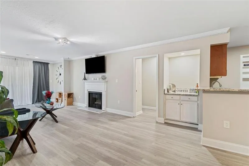 Living room featuring light wood-style floors, a fireplace, ornamental molding, and recessed lighting Living room featuring light wood-style floors, a fireplace, ornamental molding, and recessed lighting