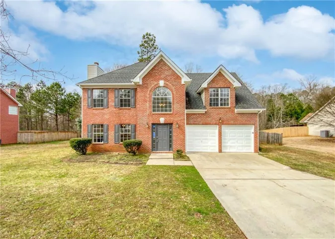 Brick exterior featuring a two-car garage, prominent arched window, dark shutters, and a front entry door