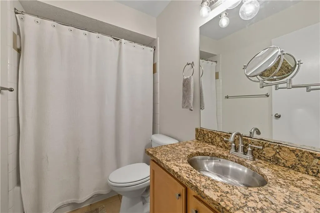 Bathroom with vanity, light tile patterned floors, and a shower with shower curtain