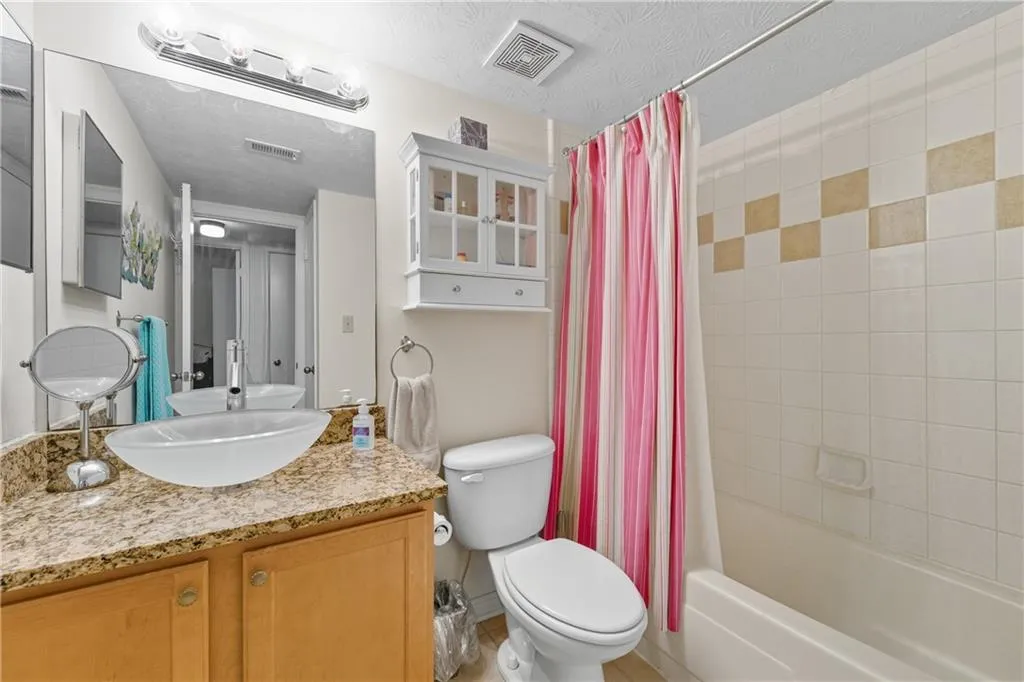 Bathroom featuring shower / tub combo with curtain, vanity, and a textured ceiling