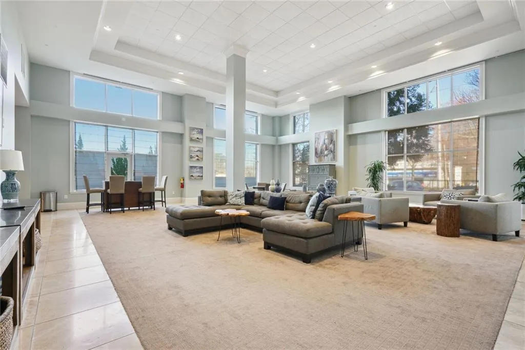 Living area with light tile patterned floors, a raised ceiling, and a high ceiling