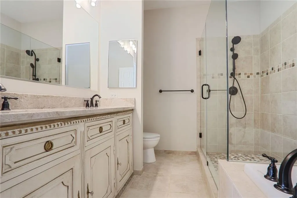 Bathroom featuring vanity, tile patterned floors, toilet, and a stall shower