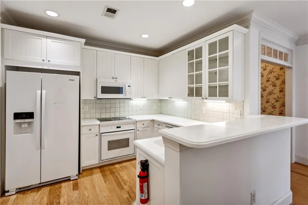 Kitchen featuring white cabinetry, light wood-type flooring, and white appliances