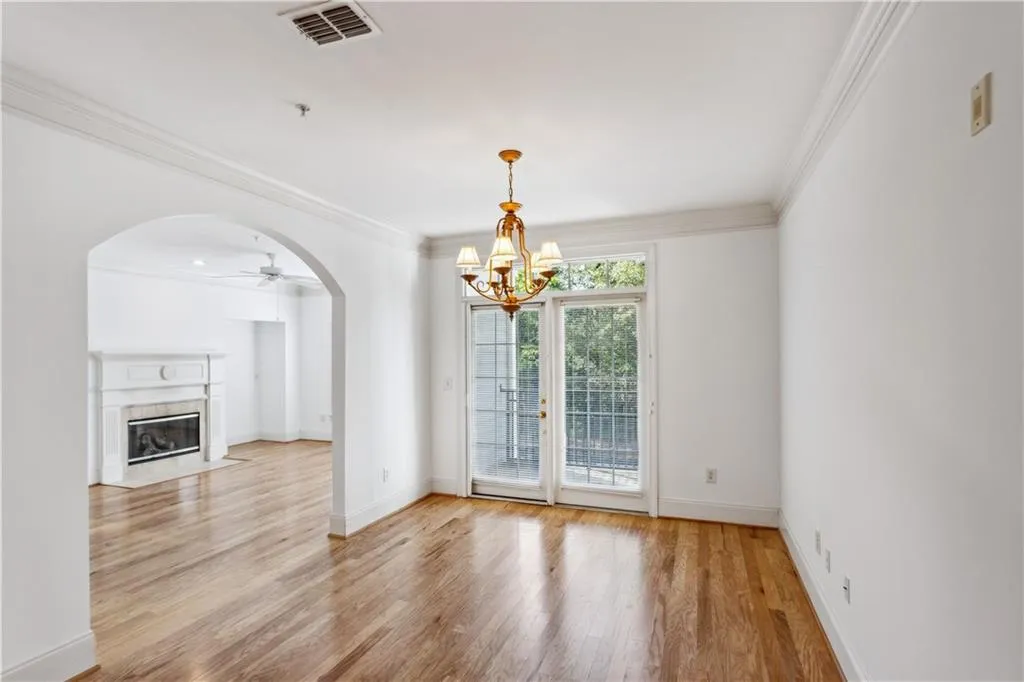 Unfurnished dining area with ceiling fan with notable chandelier, crown molding, light hardwood / wood-style flooring, and a high end fireplace
