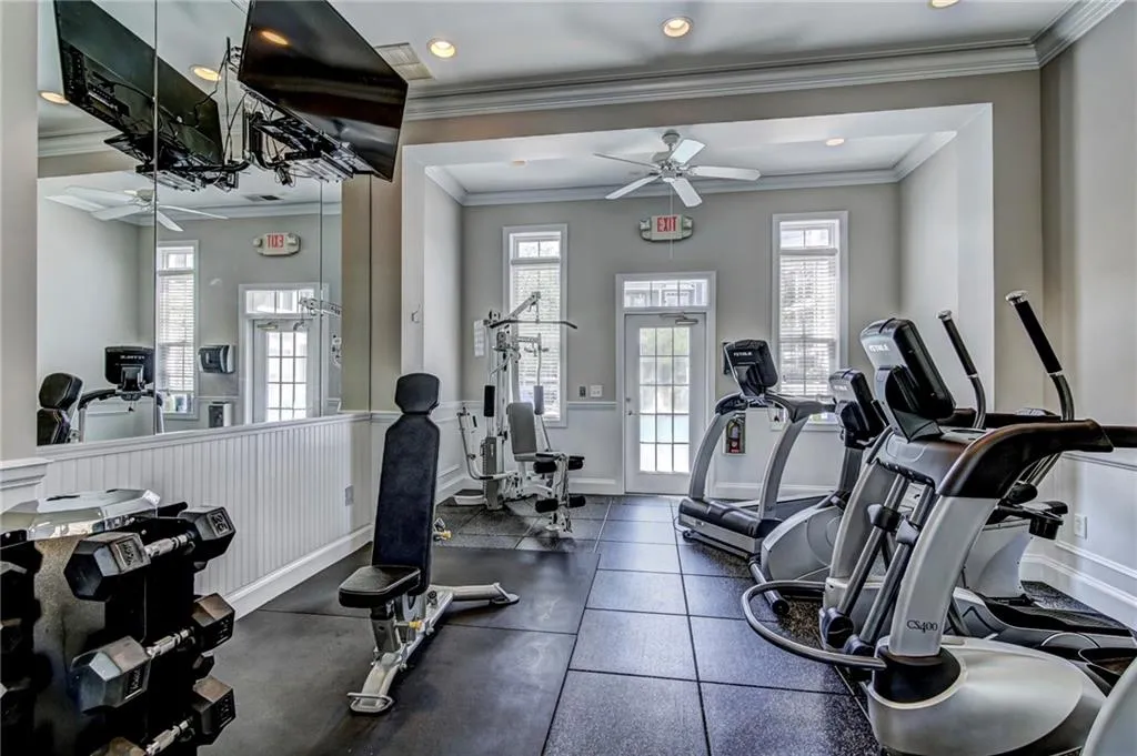 Gym featuring ornamental molding, a healthy amount of sunlight, and ceiling fan