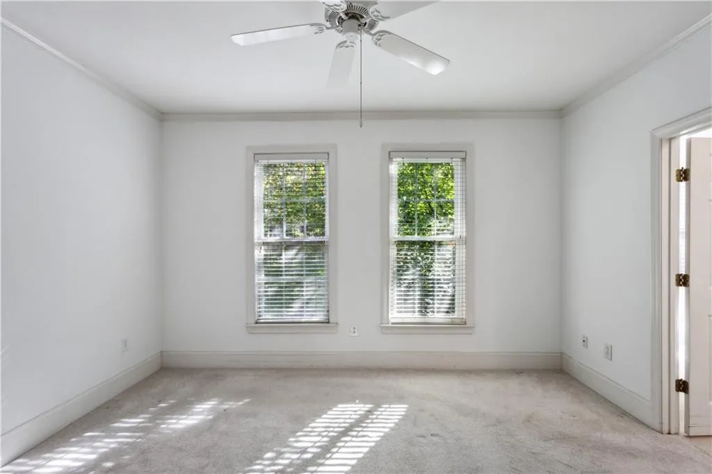 Empty room with light carpet, crown molding, and ceiling fan