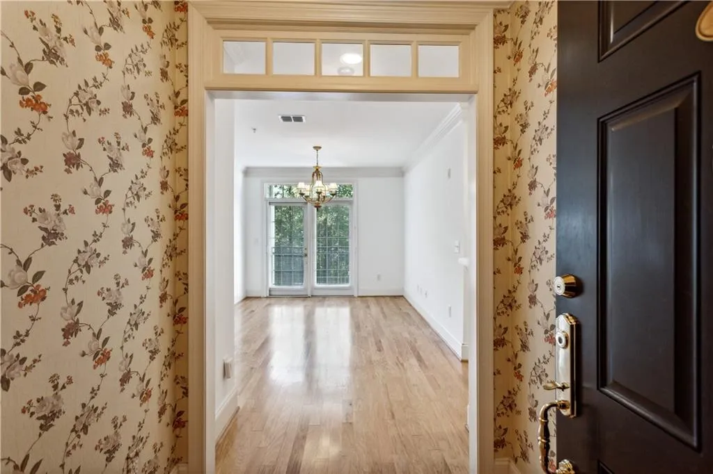 Entryway featuring french doors, a notable chandelier, ornamental molding, and light hardwood / wood-style flooring