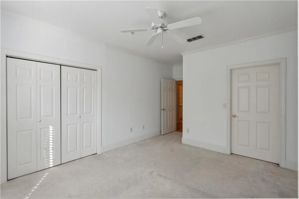 Unfurnished bedroom with light carpet, crown molding, and ceiling fan