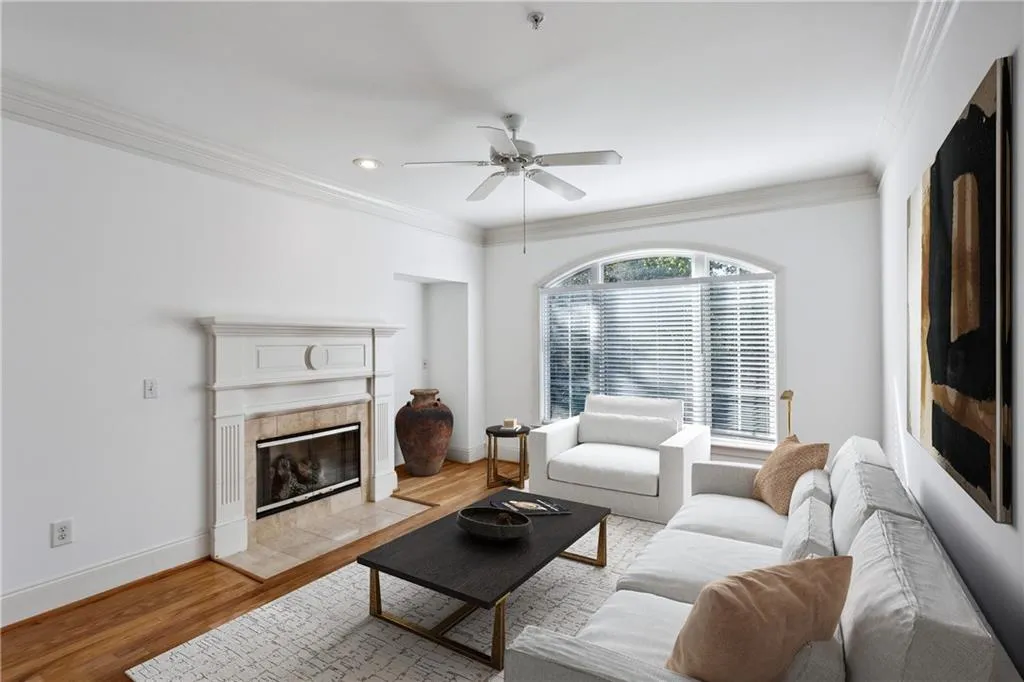 Living room with light wood-type flooring, crown molding, baseboards, and ceiling fan