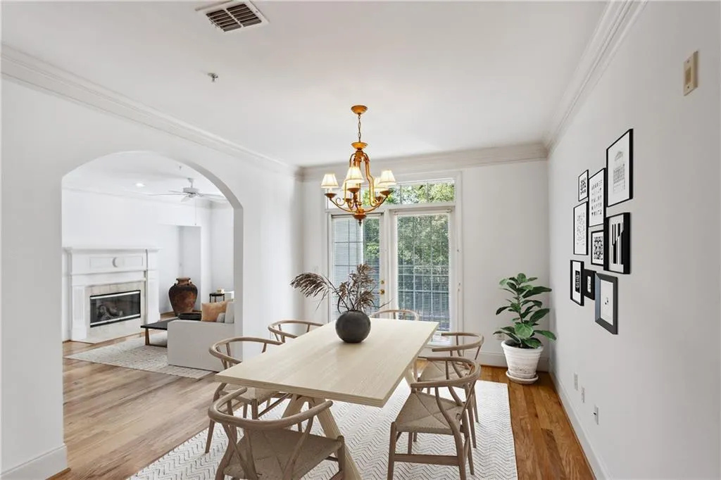 Dining space featuring a premium fireplace, light wood-type flooring, ornamental molding, arched walkways, and visible vents