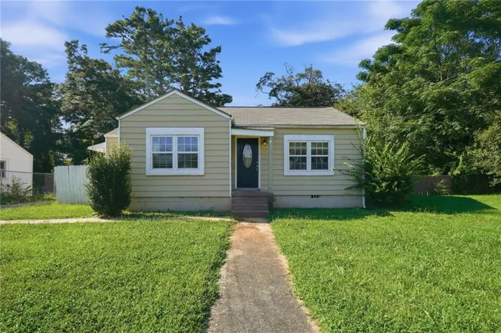 Siding exterior with multiple windows, leading to an entryway with a dark-paneled door