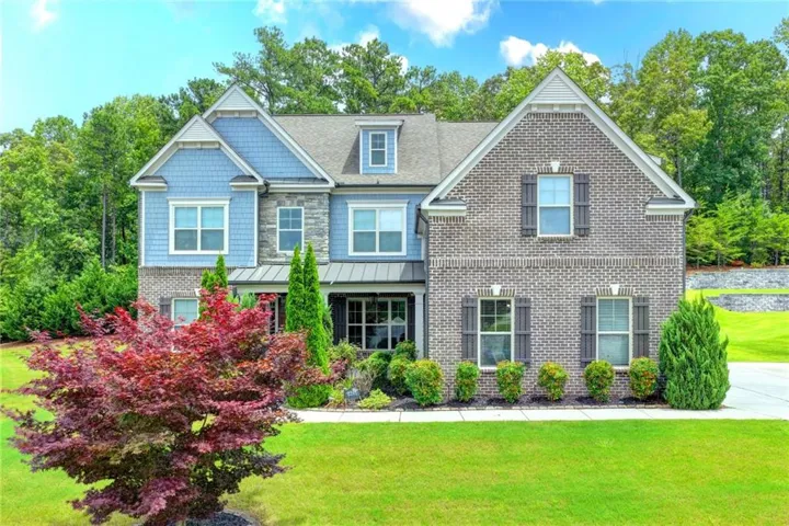Transitional-style residence showcasing a two-story brick facade, light blue siding, and stone accents