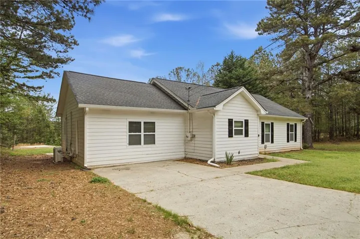 View of front facade featuring a shingled roof, a patio area, a front yard, and driveway