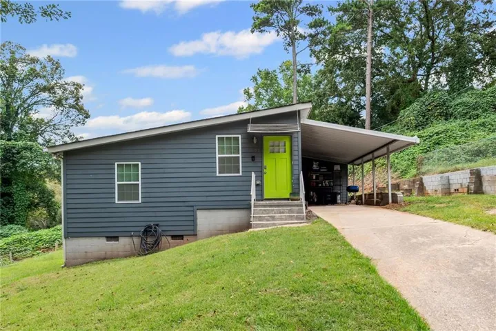 View of front of house with crawl space, driveway, a front yard, and an attached carport