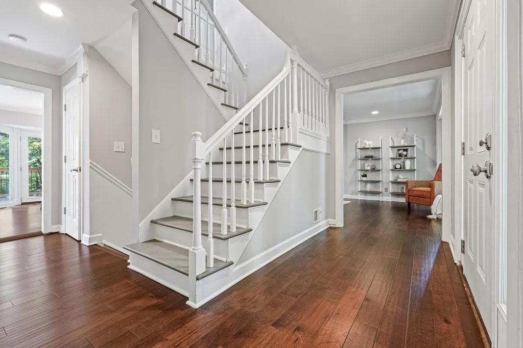 Foyer featuring wood-finish flooring, a staircase with white balusters and a dark-finish handrail, crown molding, and recessed lighting
