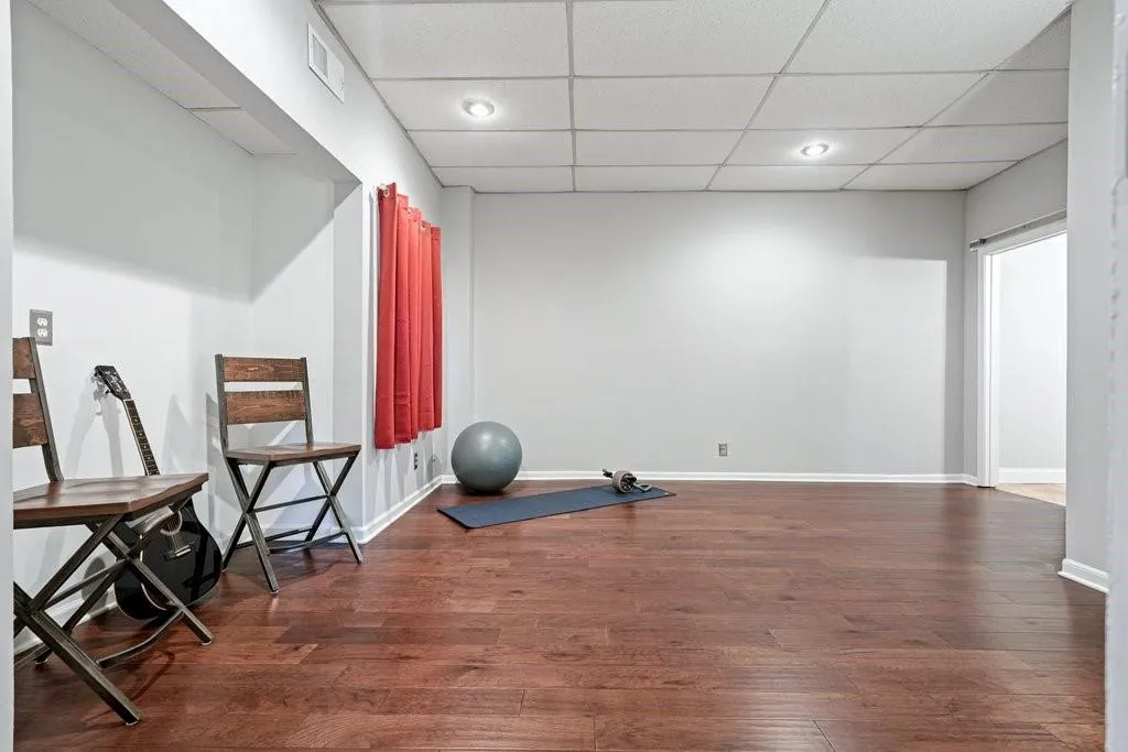 Finished room featuring wood-finish flooring, a recessed drop ceiling, and integrated recessed lighting