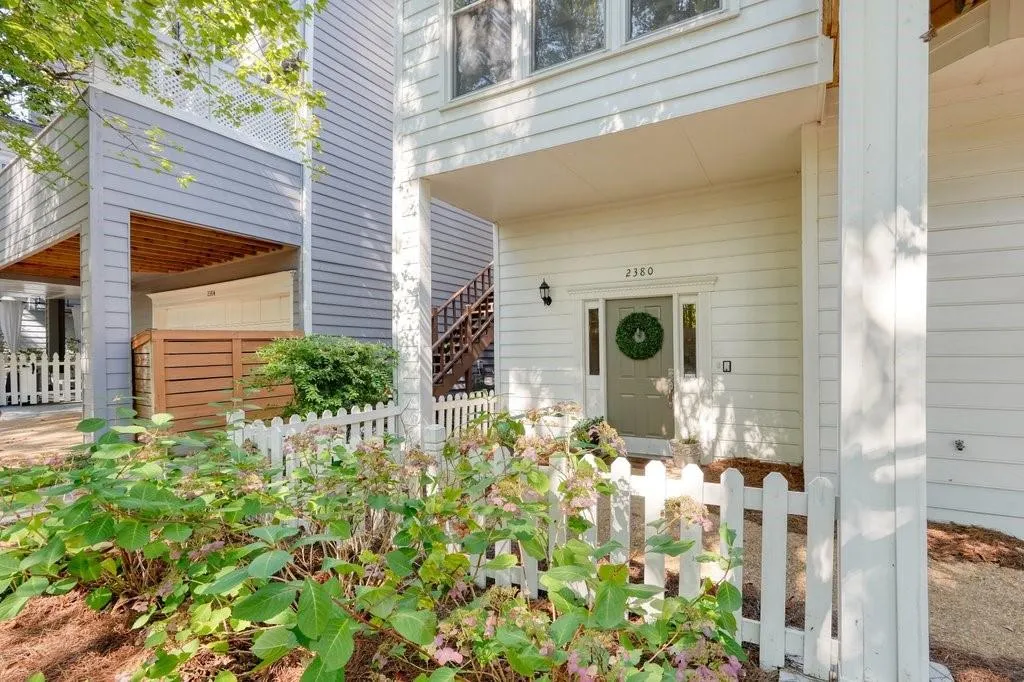 Exterior featuring horizontal lap siding, a covered entryway, a white picket fence, and wooden stair detailing