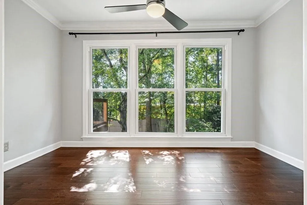 Wood-finish flooring, triple-pane window configuration, and modern ceiling fan with integrated lighting