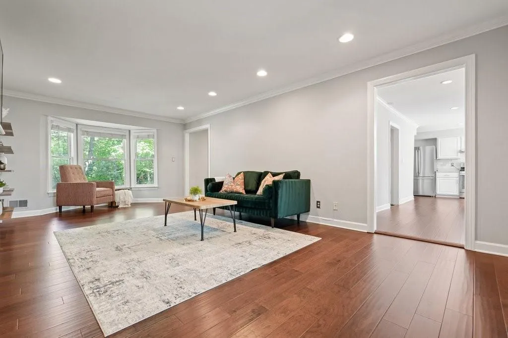 Open-concept interior featuring wood-finish flooring, recessed lighting, crown molding, and a bay window