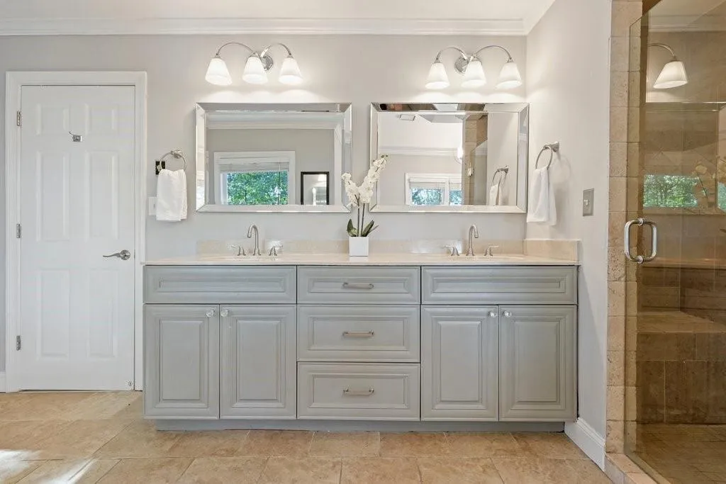 Double vanity featuring light gray cabinetry, a neutral countertop, dual rectangular mirrors, and wall-mounted three-light fixtures
