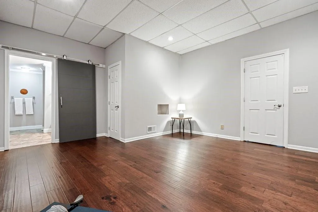 Interior space featuring wood-finish flooring, a charcoal-colored sliding barn door with brushed metal hardware, and two panel doors