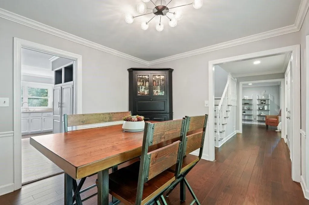 Dining area featuring wood-finish flooring, crown molding, chair rail trim, and a multi-bulb sputnik-style chandelier