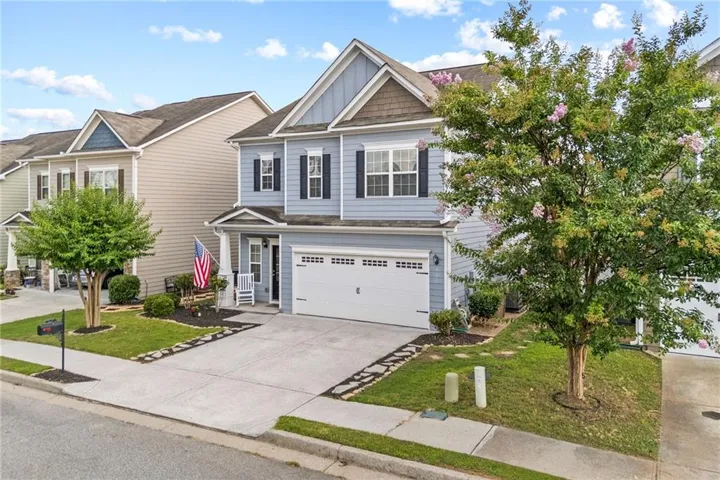 Two-story residence featuring light blue siding, a two-car garage, and a covered porch