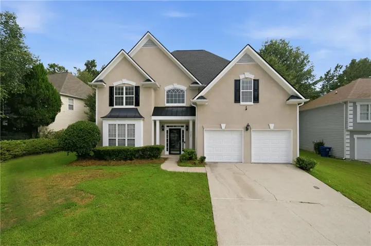 Stucco exterior featuring gabled rooflines, a covered entry, decorative shutters, and an attached two-car garage