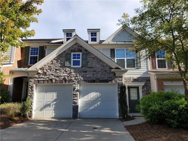 Stone and siding exterior with a two-car garage, multiple windows with shutters, and architectural gables