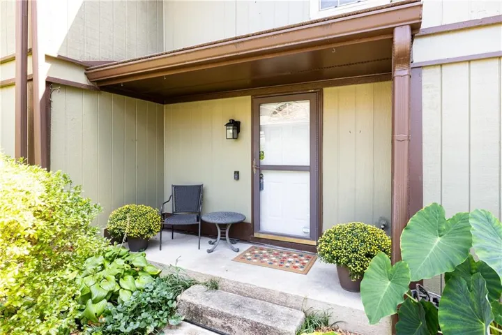 Covered entryway featuring a white storm door, board and batten siding, and an exterior wall light