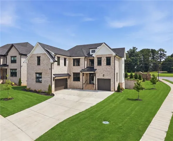 Light-colored brick exterior with black framed windows, a multi-car driveway, and manicured green lawn